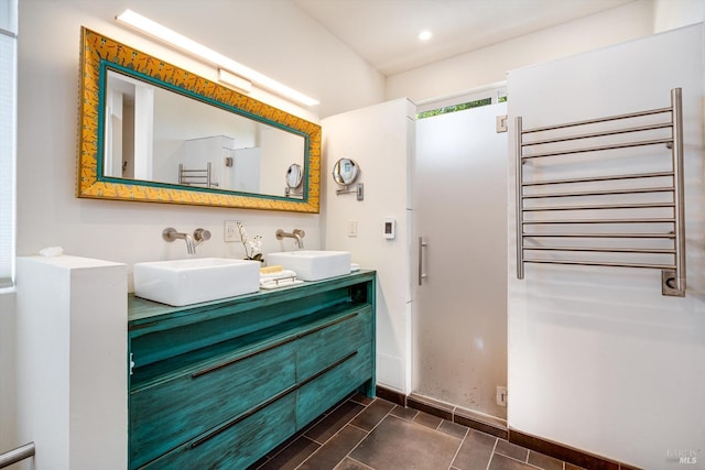 full bath featuring double vanity, a sink, radiator heating unit, and recessed lighting