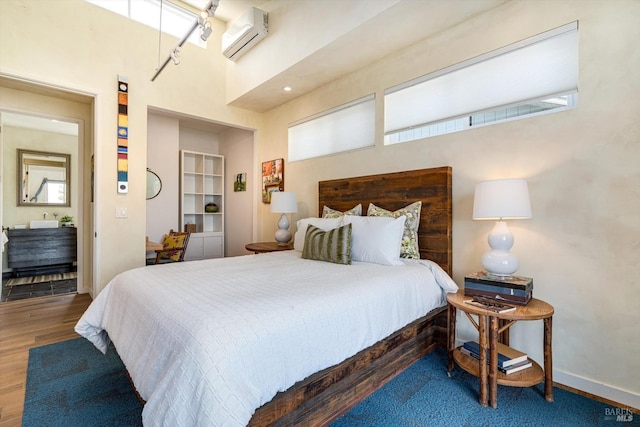 bedroom with baseboards, an AC wall unit, and wood finished floors