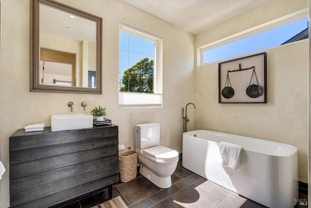 full bathroom with toilet, a soaking tub, and vanity