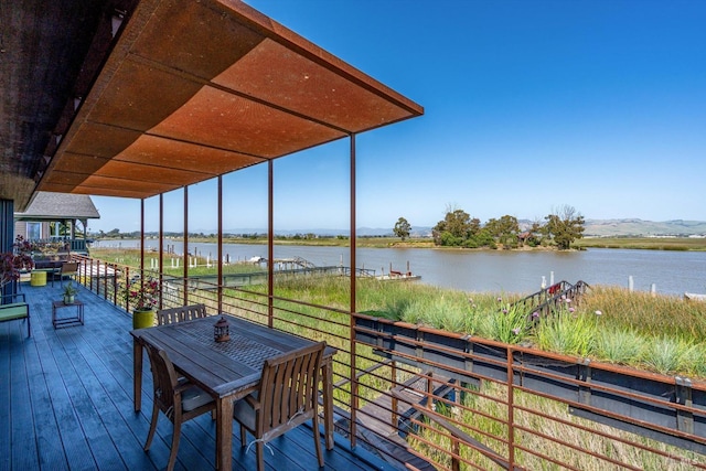 deck with a water view and outdoor dining space