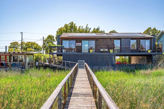 back of house featuring roof mounted solar panels