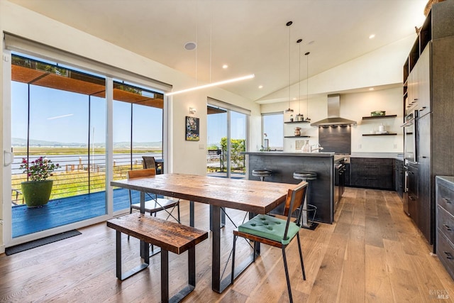 dining room with recessed lighting, lofted ceiling, and light wood-type flooring