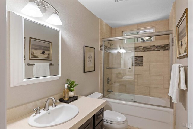 bathroom featuring toilet, visible vents, combined bath / shower with glass door, and vanity