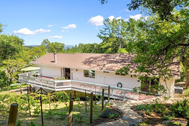 back of property with central air condition unit, a wooden deck, and roof with shingles