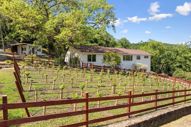 view of yard featuring an outdoor structure, fence, and a vegetable garden