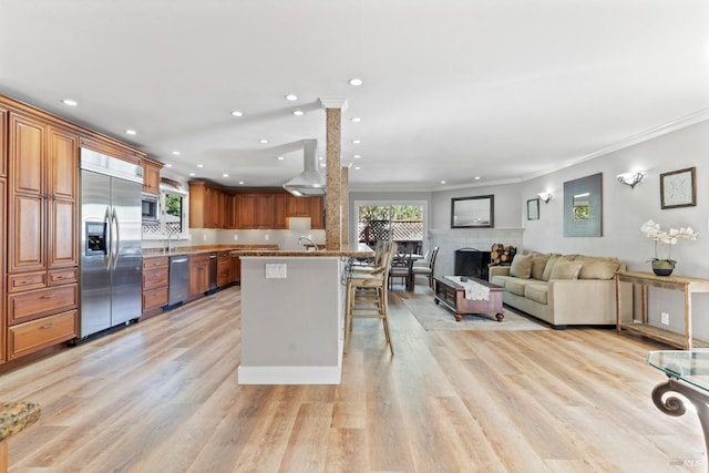 28 Washington St, Novato, CA 94947 - kitchen featuring built in appliances, a breakfast bar, a fireplace, brown cabinetry, and crown molding