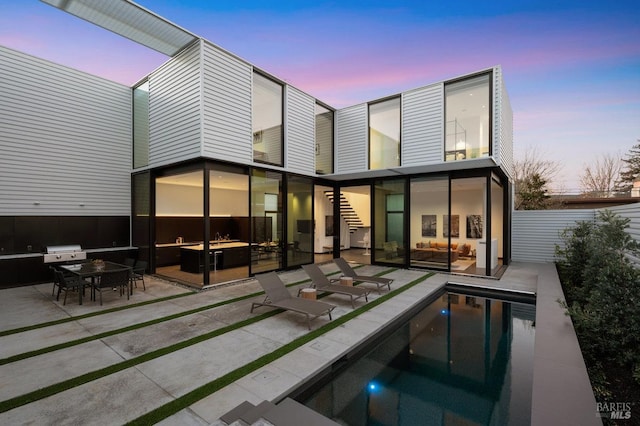 rear view of house with a fenced in pool, fence, and a patio area