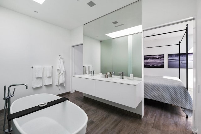ensuite bathroom with a sink, ensuite bath, double vanity, wood finished floors, and a soaking tub