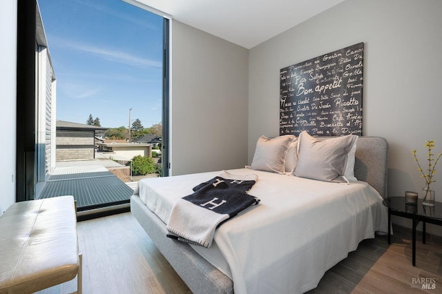 bedroom with floor to ceiling windows and wood finished floors