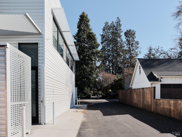 view of side of home featuring fence and driveway