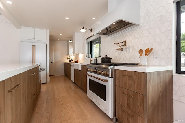 kitchen featuring a sink, white appliances, light countertops, premium range hood, and modern cabinets
