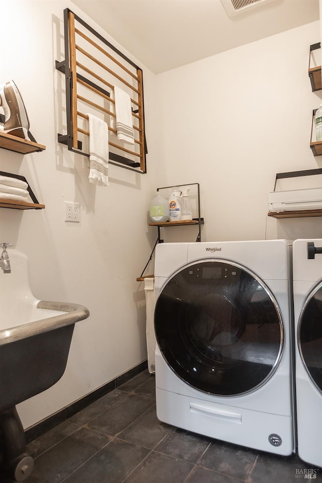 washroom with laundry area, baseboards, washer and dryer, and dark tile patterned flooring
