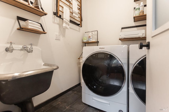 laundry room featuring washing machine and clothes dryer, laundry area, a sink, baseboards, and dark tile patterned floors