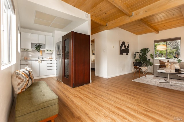 living area with baseboards, beam ceiling, wood ceiling, and light wood-style floors