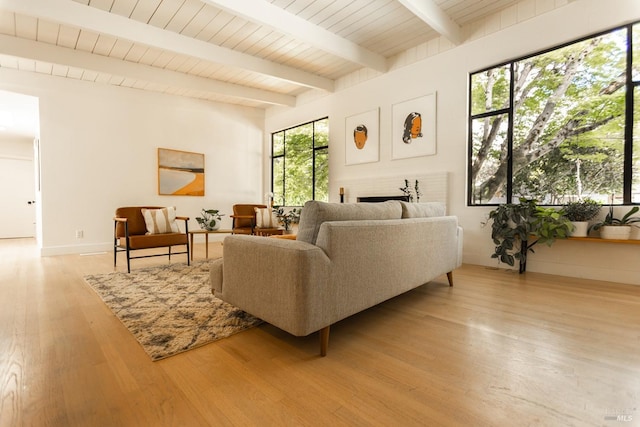 living area featuring a fireplace, beam ceiling, and light wood-style flooring