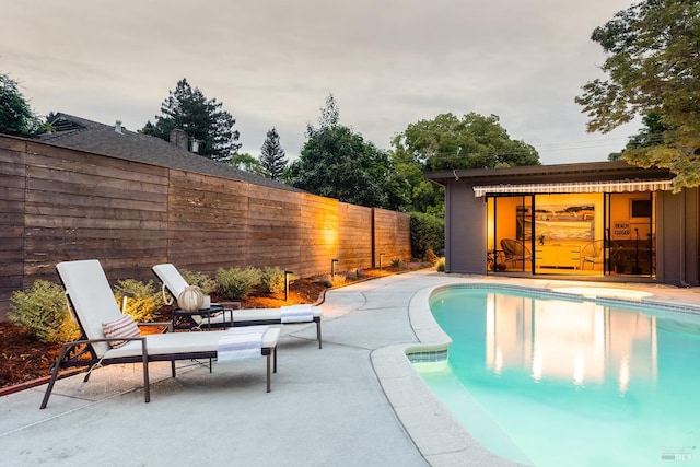 view of swimming pool featuring a fenced backyard, a fenced in pool, an outdoor structure, and a patio area