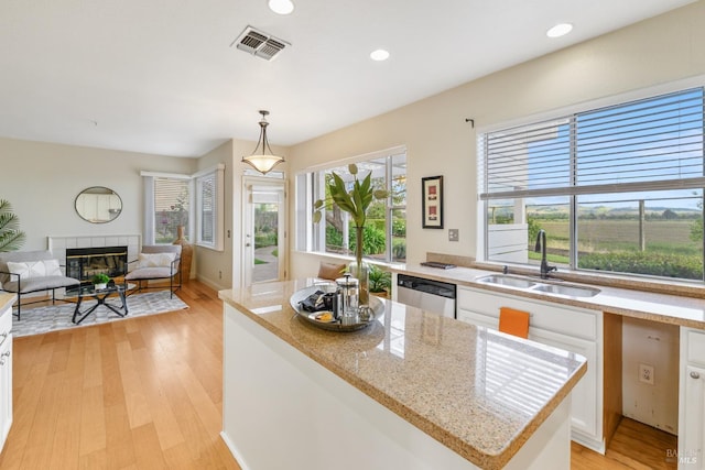 kitchen with visible vents, dishwasher, a sink, white cabinets, and light wood finished floors