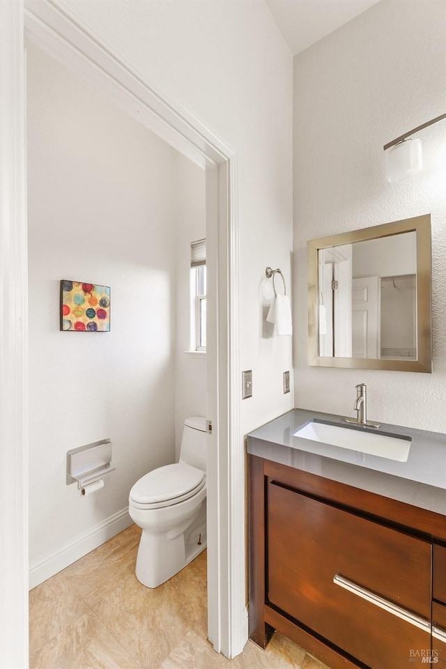 bathroom with toilet, baseboards, and vanity