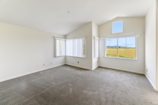 carpeted spare room featuring baseboards and lofted ceiling