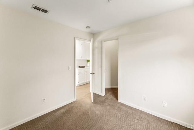 unfurnished bedroom featuring baseboards, visible vents, and light carpet