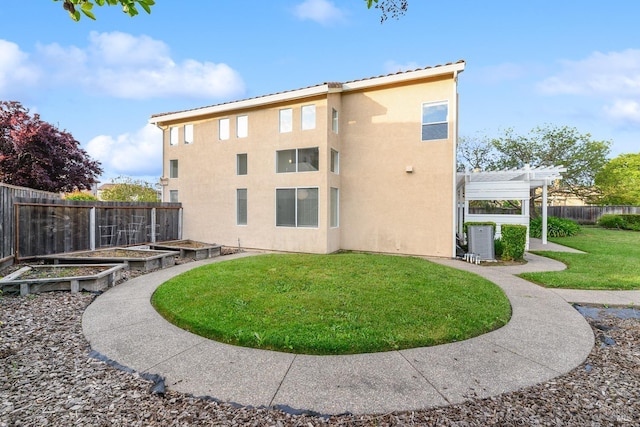 rear view of house featuring a pergola, stucco siding, a vegetable garden, a fenced backyard, and a yard