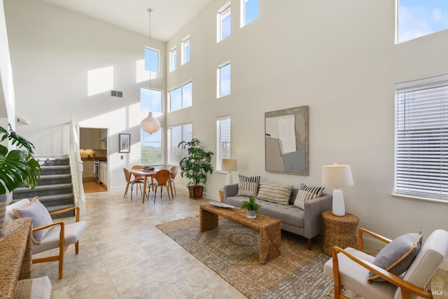 living room featuring visible vents, a high ceiling, and a wealth of natural light