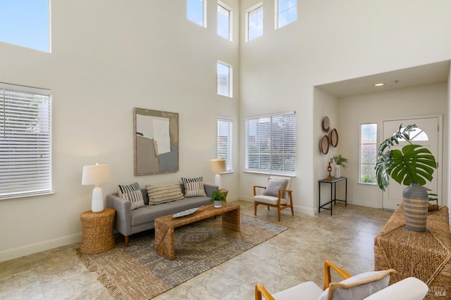 living area with baseboards, a high ceiling, and a healthy amount of sunlight