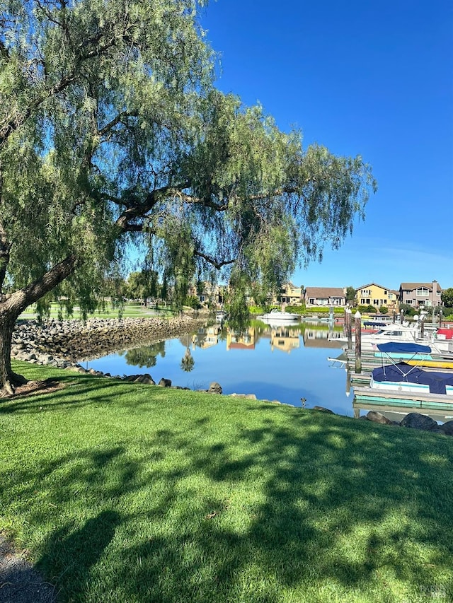 view of dock featuring a lawn and a water view