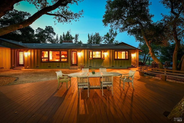 rear view of property with board and batten siding, a wooden deck, a chimney, and entry steps
