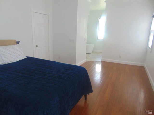 bedroom featuring baseboards, multiple windows, and wood finished floors