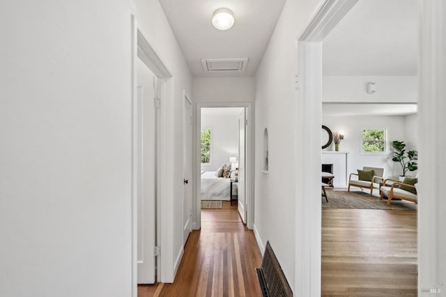 hall featuring visible vents, wood finished floors, and attic access