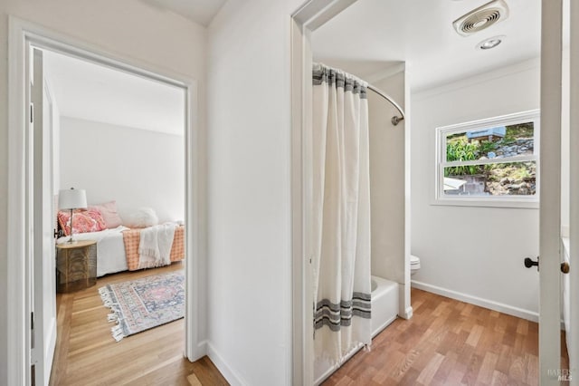 ensuite bathroom featuring baseboards, toilet, wood finished floors, and visible vents