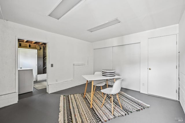dining room featuring finished concrete flooring and attic access
