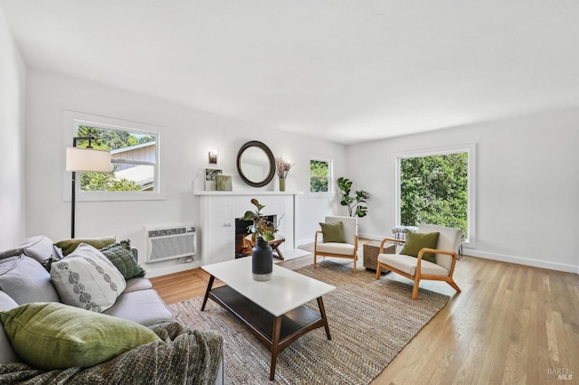 living room with baseboards, an AC wall unit, and light wood-type flooring