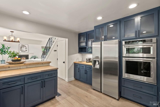 269 Castro St, Lagunitas, CA 94938 - kitchen featuring glass insert cabinets, decorative backsplash, appliances with stainless steel finishes, butcher block counters, and light wood-style floors