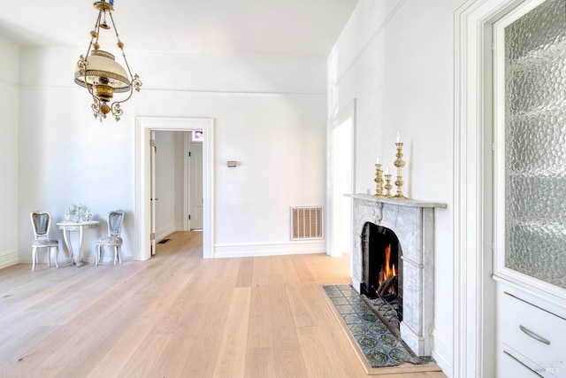 living room featuring visible vents, light wood-style flooring, baseboards, and a premium fireplace