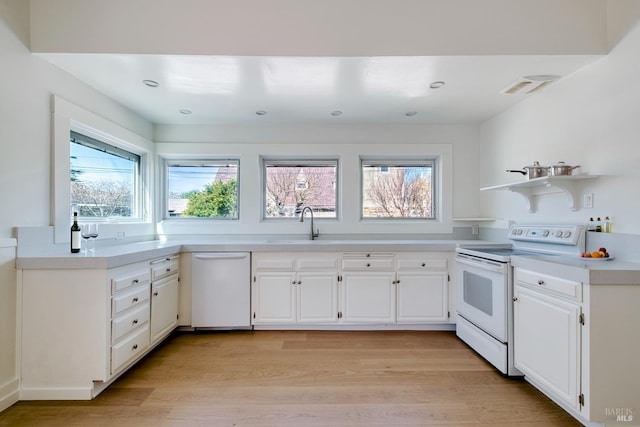 kitchen with white appliances, white cabinets, light wood-style flooring, and light countertops