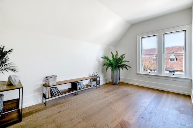 additional living space with baseboards, wood finished floors, and vaulted ceiling