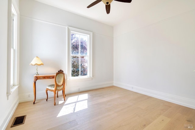 interior space with a ceiling fan, baseboards, visible vents, and light wood-type flooring