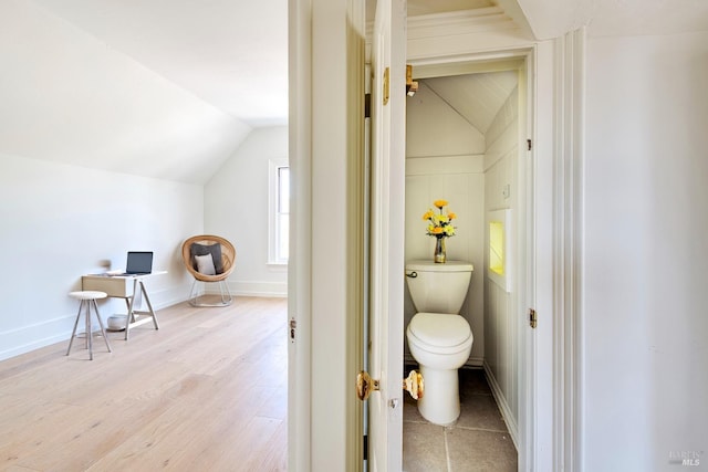 bathroom featuring baseboards, toilet, wood finished floors, and lofted ceiling