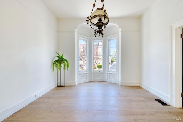 unfurnished dining area featuring baseboards, wood finished floors, and visible vents
