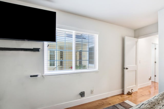 unfurnished bedroom featuring baseboards, multiple windows, and light wood-style floors