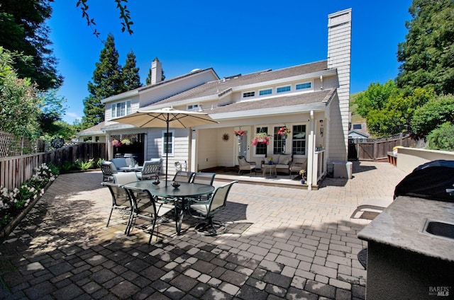 rear view of property with a fenced backyard, a patio, a chimney, and an outdoor living space