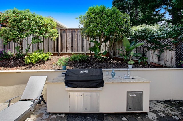 view of patio / terrace featuring fence, a sink, and area for grilling