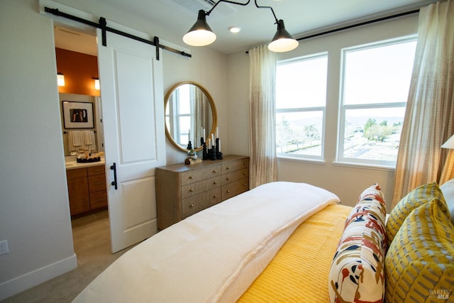 carpeted bedroom featuring ensuite bathroom, a barn door, and multiple windows