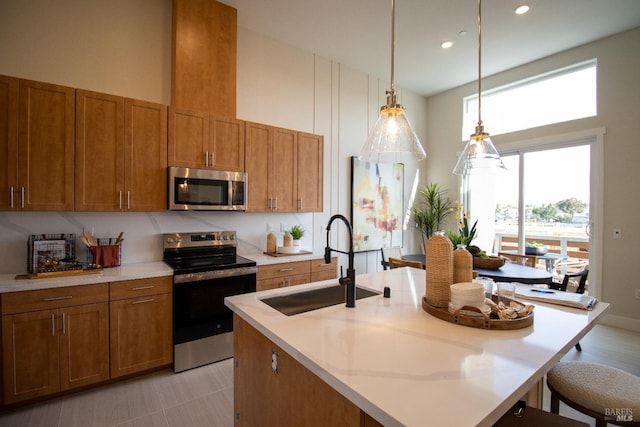 kitchen featuring appliances with stainless steel finishes, brown cabinetry, a sink, and a healthy amount of sunlight
