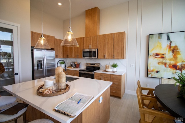 kitchen with brown cabinetry, appliances with stainless steel finishes, hanging light fixtures, a sink, and a high ceiling