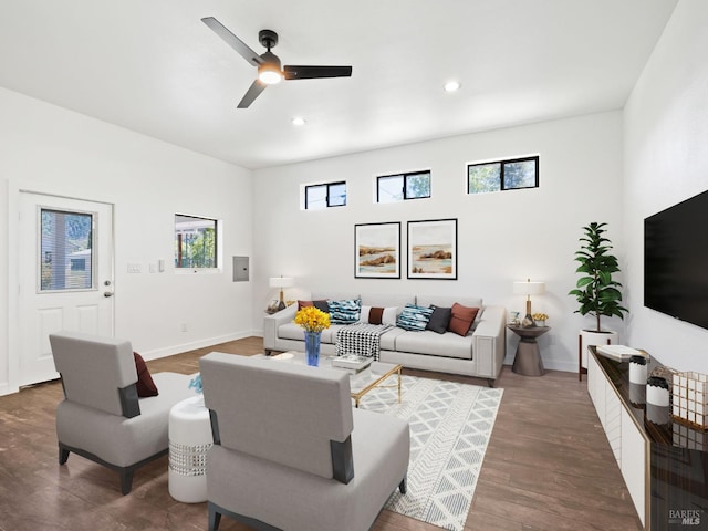 living area with plenty of natural light, a ceiling fan, dark wood-style flooring, and baseboards