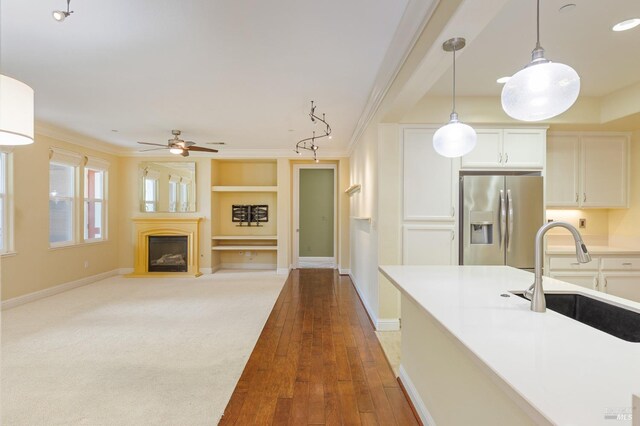 kitchen featuring ceiling fan, crown molding, hanging light fixtures, a sink, and stainless steel fridge