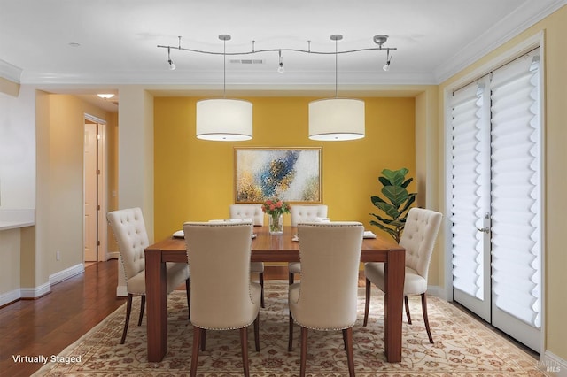 dining room with visible vents, ornamental molding, wood finished floors, and a healthy amount of sunlight